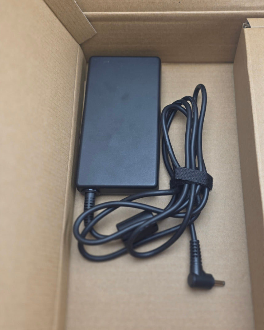 Black power adapter with cable inside a cardboard box